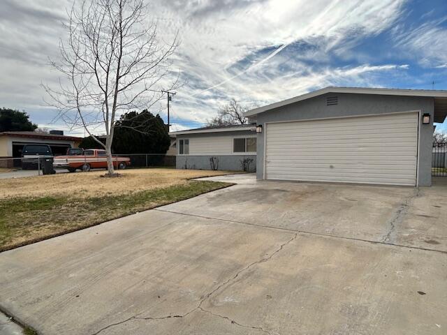 view of front of home with a garage, concrete driveway, stucco siding, and fence