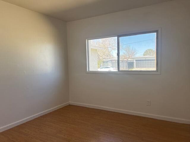 empty room with baseboards and wood finished floors