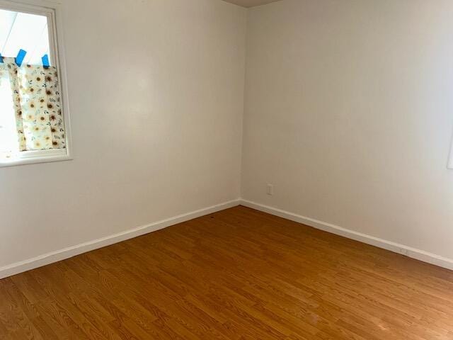 empty room with light wood-type flooring and baseboards