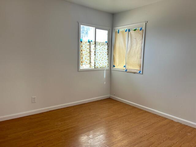 unfurnished room with ceiling fan, a wall mounted air conditioner, and light wood-type flooring