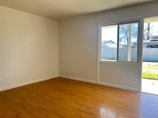 unfurnished room with baseboards and wood finished floors