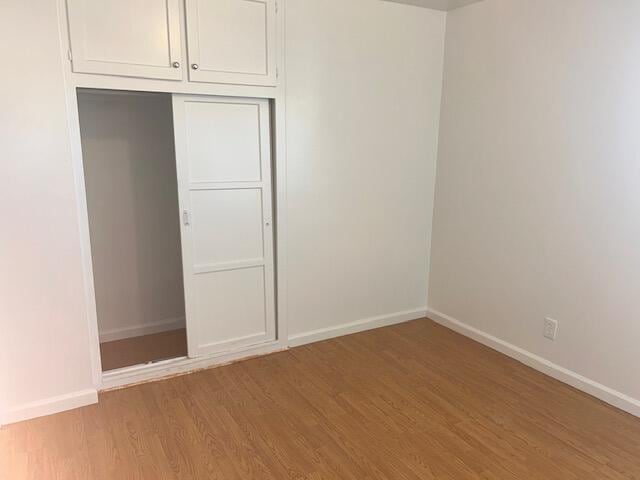 unfurnished bedroom with a closet, baseboards, and light wood finished floors