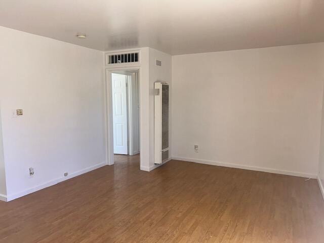 empty room featuring visible vents, baseboards, and wood finished floors