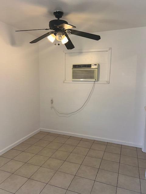 unfurnished room with a ceiling fan, baseboards, and a wall mounted AC