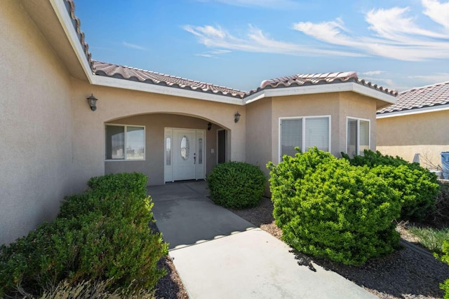 property entrance with stucco siding and a tiled roof