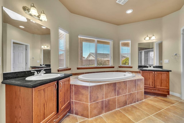 bathroom featuring a stall shower, a bath, a sink, and two vanities