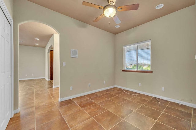 empty room featuring baseboards, recessed lighting, a ceiling fan, arched walkways, and light tile patterned floors