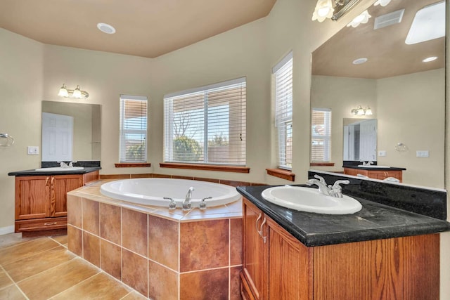 bathroom featuring visible vents, two vanities, a sink, a garden tub, and tile patterned flooring