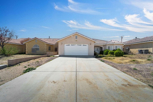 view of front facade featuring stucco siding, a tile roof, a garage, and concrete driveway