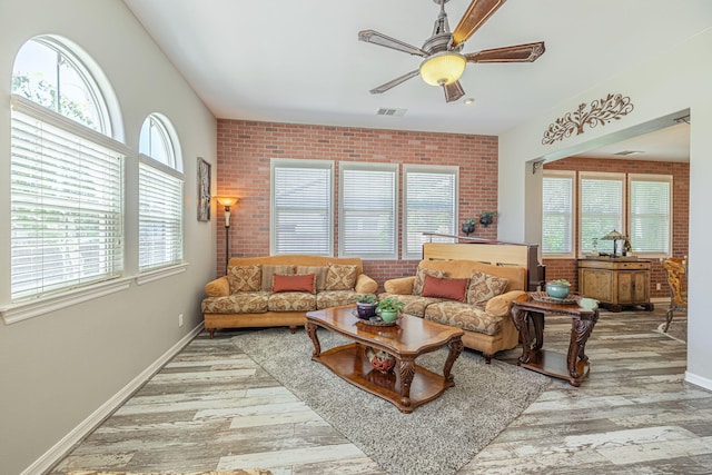 living room with wood-type flooring, ceiling fan, and brick wall