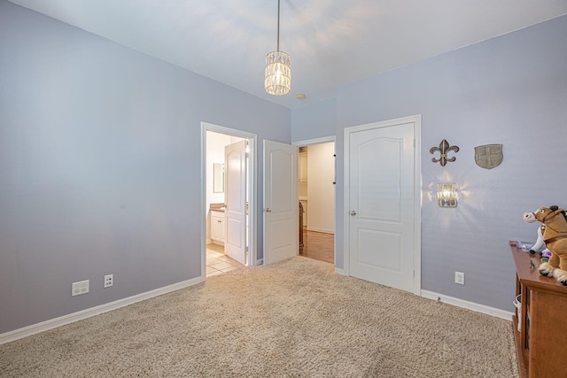 unfurnished bedroom featuring light carpet and ensuite bath