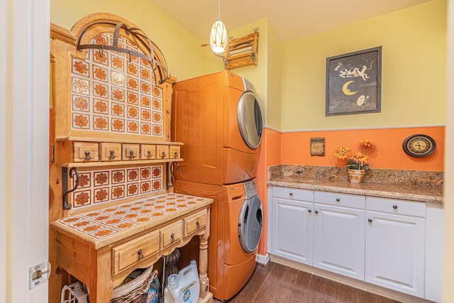 washroom featuring cabinets, stacked washing maching and dryer, and dark wood-type flooring