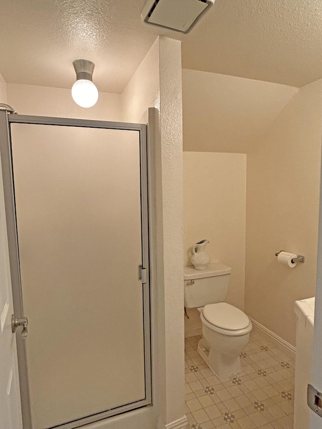 bathroom featuring a textured ceiling, an enclosed shower, and toilet