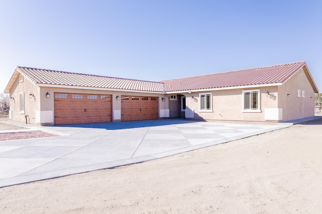 ranch-style house featuring a tile roof, a garage, driveway, and stucco siding