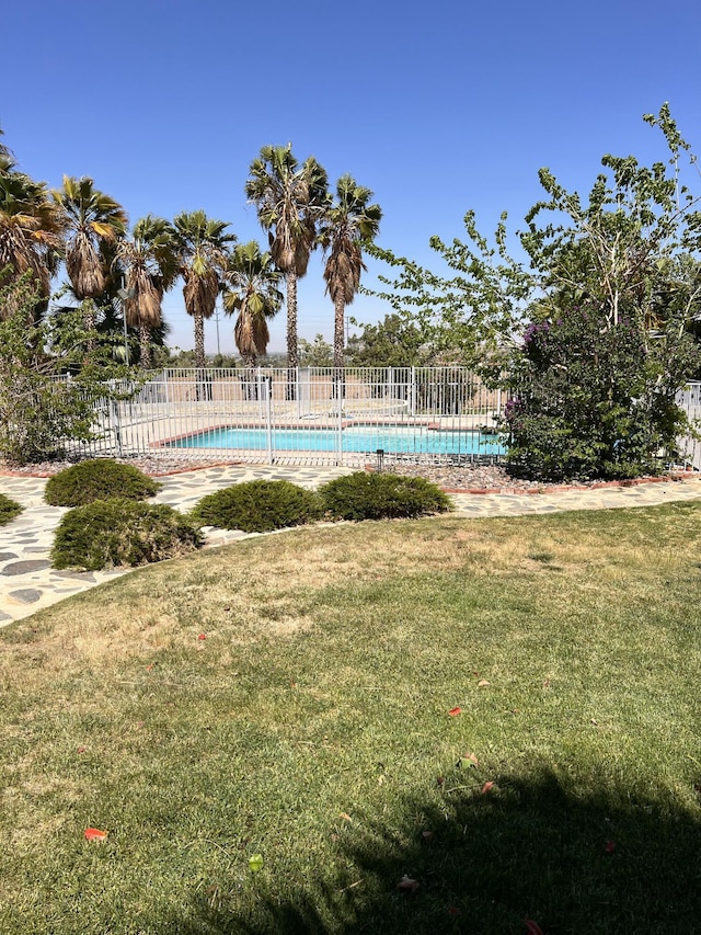 view of swimming pool featuring a yard, fence, and a fenced in pool