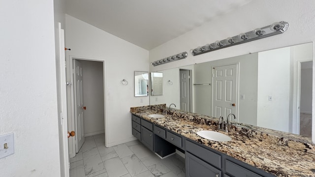full bathroom with a sink, double vanity, marble finish floor, and lofted ceiling
