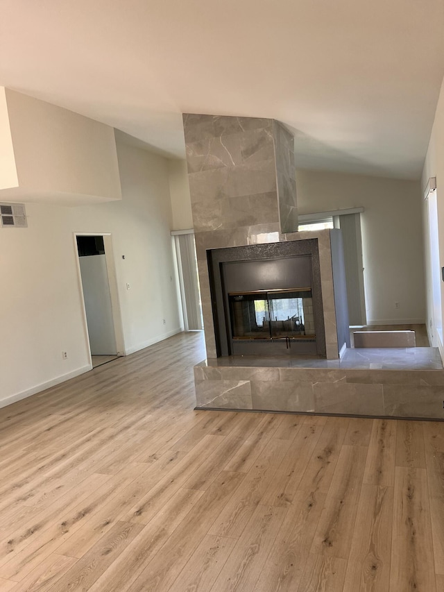 room details featuring a tiled fireplace, visible vents, baseboards, and wood finished floors