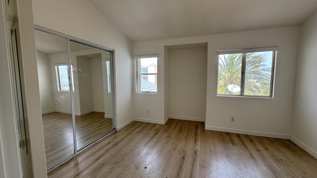 unfurnished bedroom with a closet, baseboards, multiple windows, and light wood finished floors
