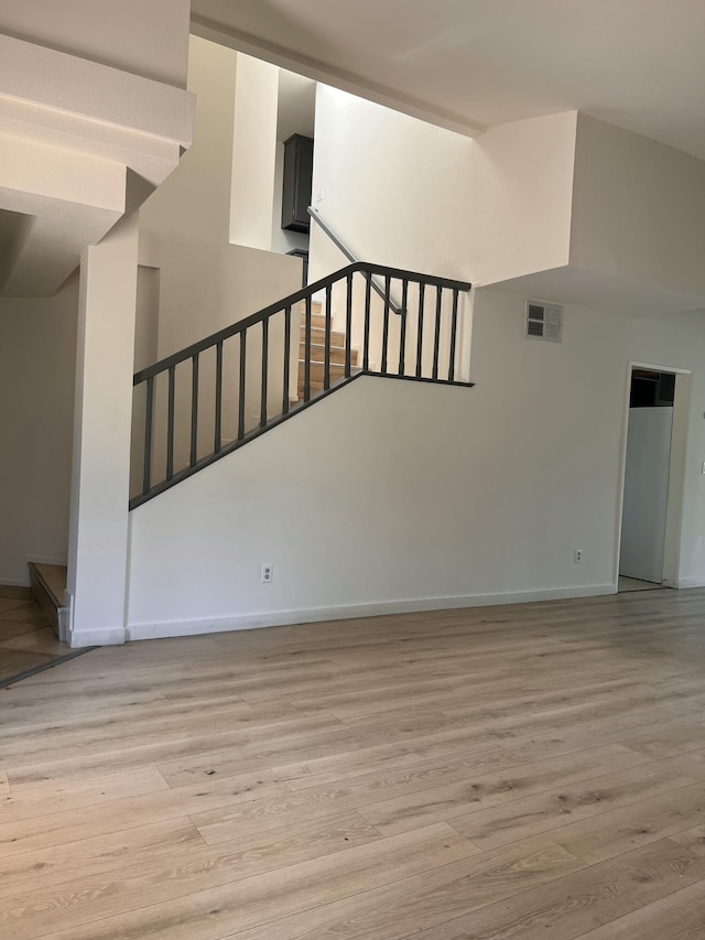 unfurnished living room with visible vents, light wood-type flooring, and baseboards