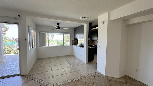 interior space featuring light tile patterned floors, visible vents, baseboards, and ceiling fan