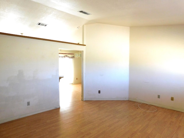 spare room featuring light hardwood / wood-style floors and vaulted ceiling