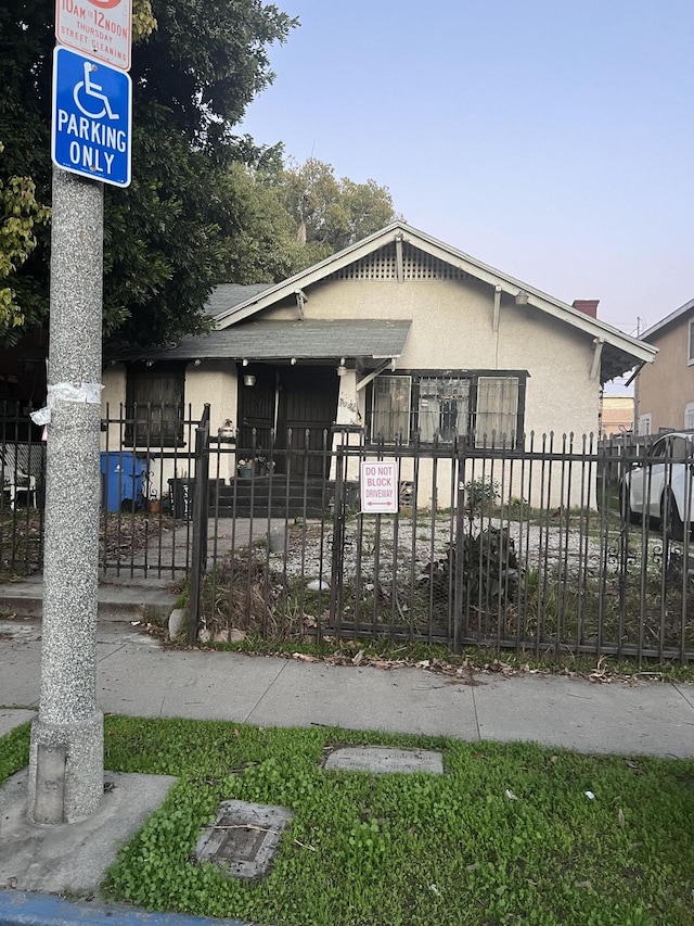 bungalow featuring fence and stucco siding