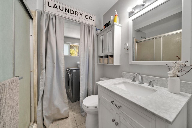 bathroom with toilet, a shower with shower door, vanity, washer and dryer, and tile patterned floors