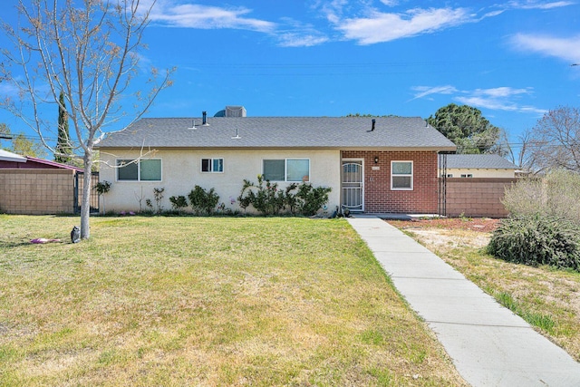 view of front facade with brick siding, fence, and a front yard