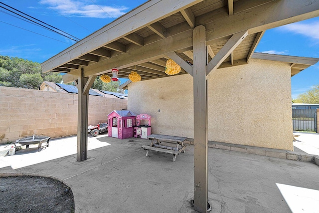 view of patio featuring an outdoor fire pit and fence