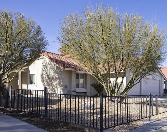 view of front of home with a garage, a tiled roof, a fenced front yard, and stucco siding