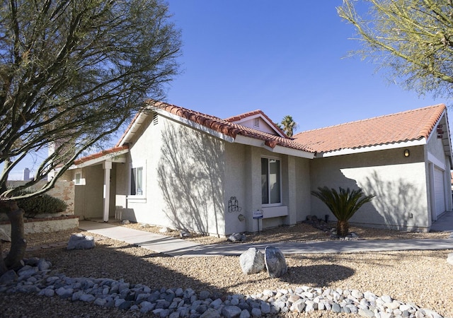 exterior space featuring a garage, stucco siding, and a tiled roof