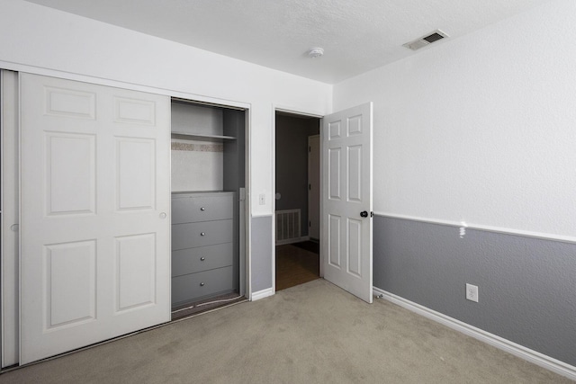 unfurnished bedroom with a closet, light colored carpet, visible vents, and baseboards