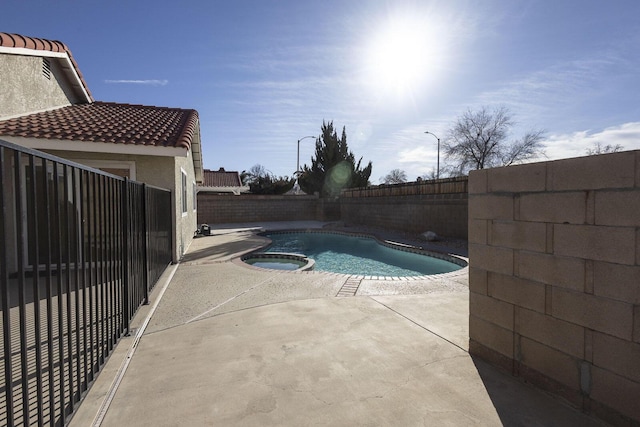 view of swimming pool featuring a patio, a fenced backyard, and a pool with connected hot tub