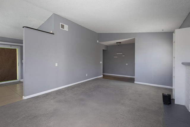 unfurnished living room featuring baseboards, visible vents, vaulted ceiling, a textured ceiling, and carpet flooring