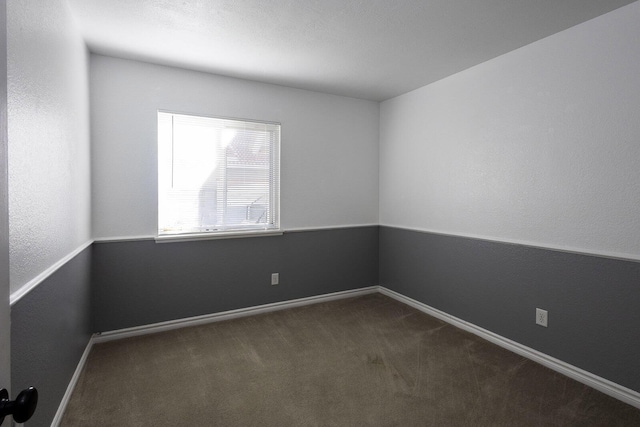 empty room with baseboards and dark colored carpet