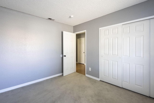 unfurnished bedroom with light carpet, baseboards, visible vents, a textured ceiling, and a closet