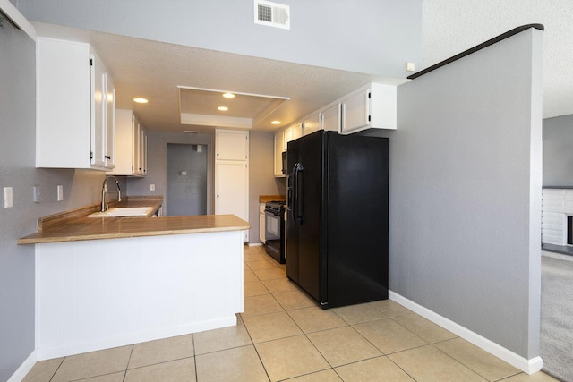 kitchen featuring baseboards, a raised ceiling, light countertops, black appliances, and white cabinetry