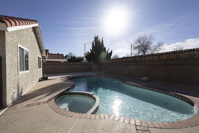 view of swimming pool with a fenced backyard and a pool with connected hot tub