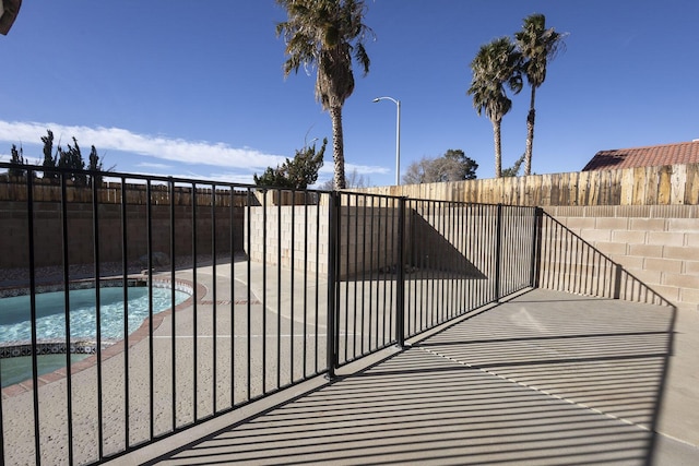 view of gate featuring fence, a fenced in pool, and a patio