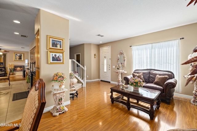 39243 Nicole Dr, Palmdale, CA 93551 - living area featuring a warm lit fireplace, light wood-style flooring, stairway, and recessed lighting