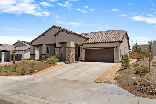 mediterranean / spanish house featuring stucco siding, roof mounted solar panels, a garage, concrete driveway, and a tiled roof