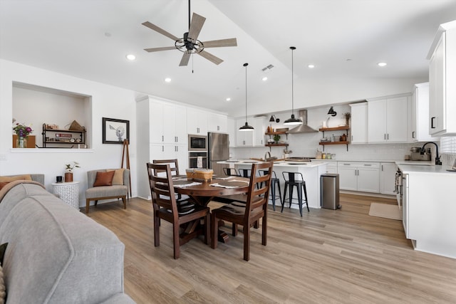 dining area with ceiling fan, vaulted ceiling, light wood-type flooring, and recessed lighting