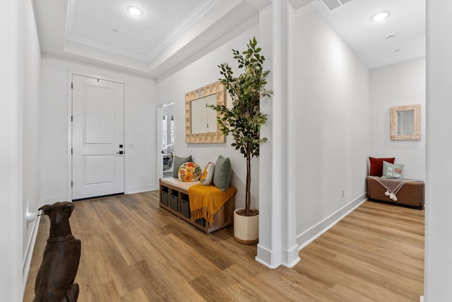 foyer with light wood finished floors, crown molding, a raised ceiling, baseboards, and recessed lighting