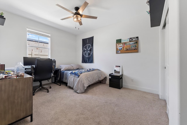 bedroom featuring light colored carpet, a desk, a ceiling fan, and baseboards