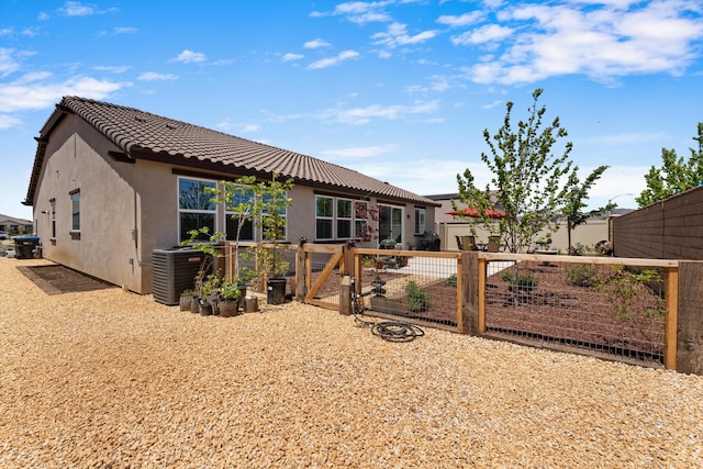 rear view of property with stucco siding, a gate, a tiled roof, and central AC