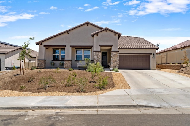 mediterranean / spanish house featuring an attached garage, stucco siding, stone siding, and driveway