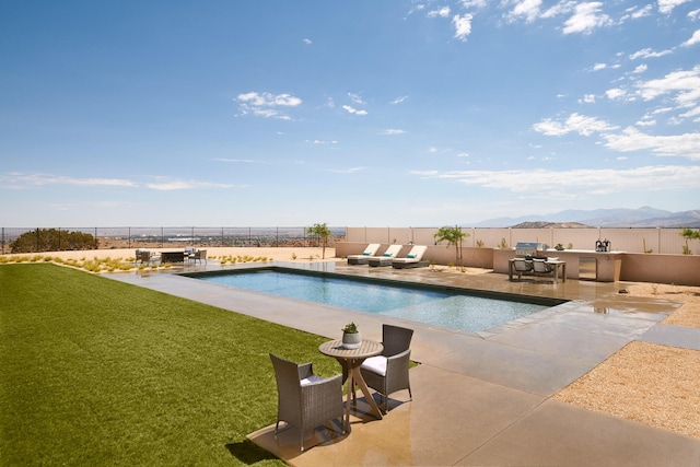 view of pool with a mountain view, a patio area, and a lawn