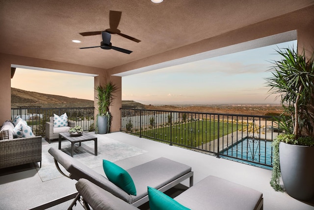 patio terrace at dusk with outdoor lounge area, a mountain view, a fenced in pool, and ceiling fan