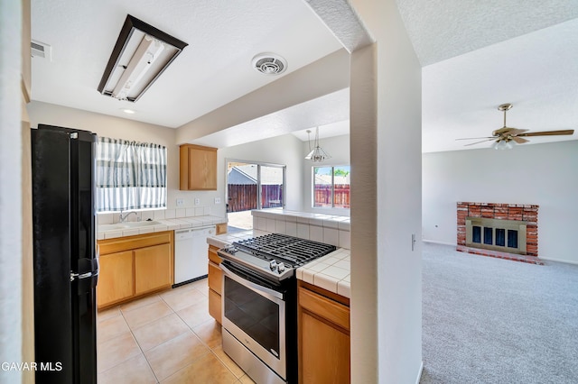 3524 San Jacinto Ave, Rosamond, CA 93560 - kitchen featuring freestanding refrigerator, stainless steel range with gas stovetop, white dishwasher, tile countertops, and a ceiling fan