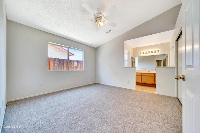 3524 San Jacinto Ave, Rosamond, CA 93560 - unfurnished bedroom with light colored carpet, vaulted ceiling, ensuite bath, a textured ceiling, and a ceiling fan